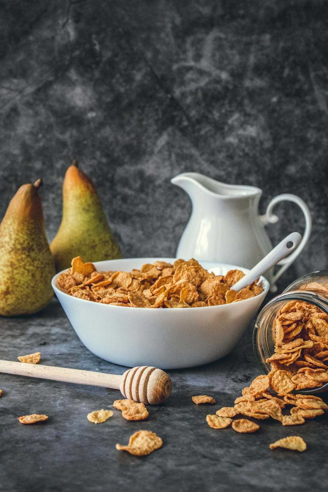 Cornflakes op tafel met 2 peren en een honingverdeler